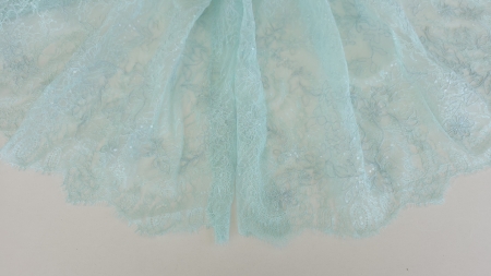 dantela chantilly verde mint cu micropaiete asezata pe masa in falduri