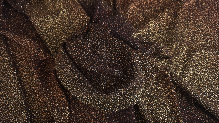 Falduri late de jerse cu particule glitter arămii pe fond negru