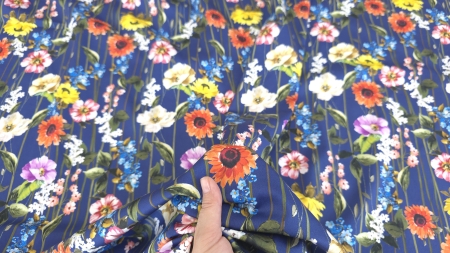 Poplin elastic floral la metru ținut în mână cu flori multicolore pe toată suprafața