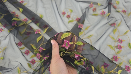 tul negru cu flori fucsia brodate ținut în mână