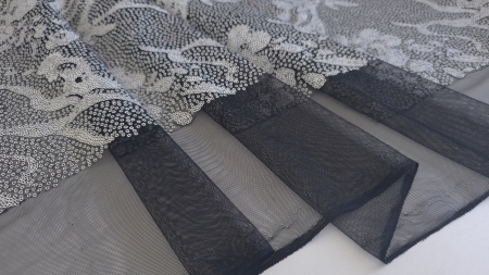 Tulle negru fin vizibil sub zona paietată și între faldurile materialului