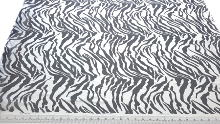 voal georgette din mătase naturală cu imprimeu zebra negru alb desfășurat pe masă cu riglă de croitorie