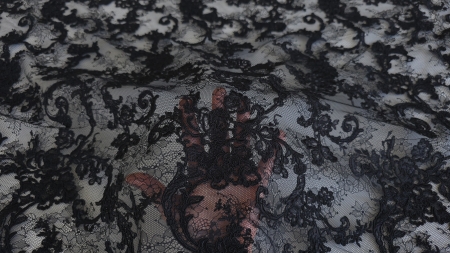 Dantelă cu motiv floral negru așezată pe palmă