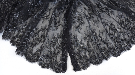 Falduri de tul negru transparent, cu broderia mai densă spre margine