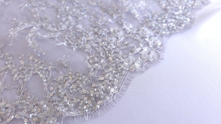 Margine festonată cu franjuri subțiri și broderie accesorizată, în plan apropiat pe fundal alb