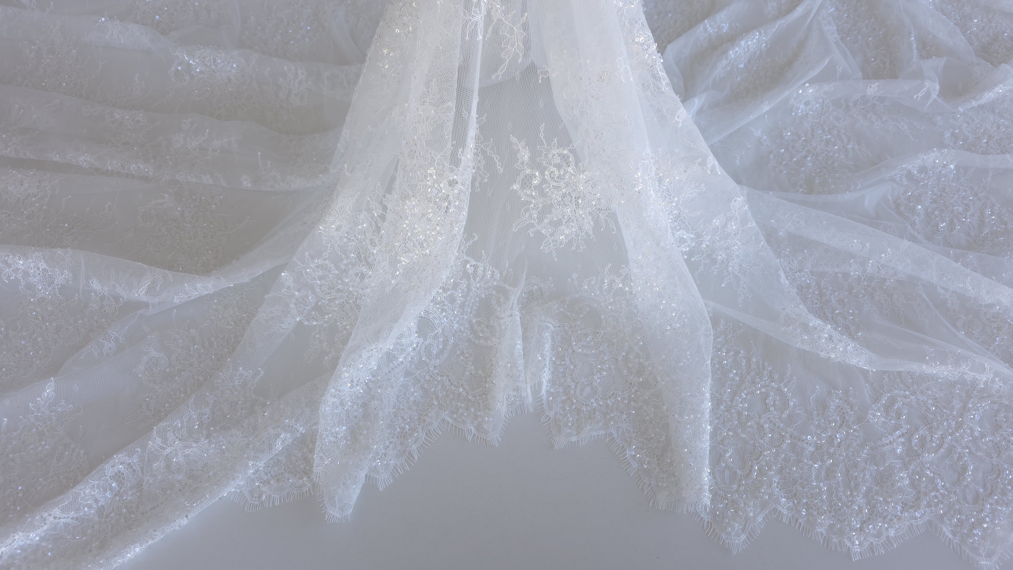 Material translucid fotografiat în cădere, cu motive florale distribuite uniform