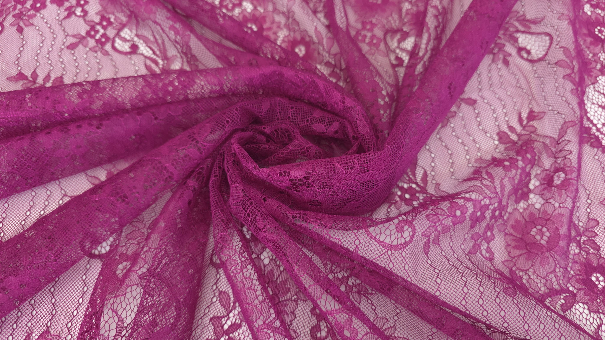Țesătură transparentă magenta răsucită în spirală, cu pliuri radiale