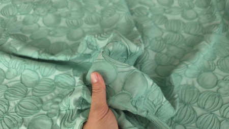 Material verde mint tinut in mana, cu forme bombate pe fond fin